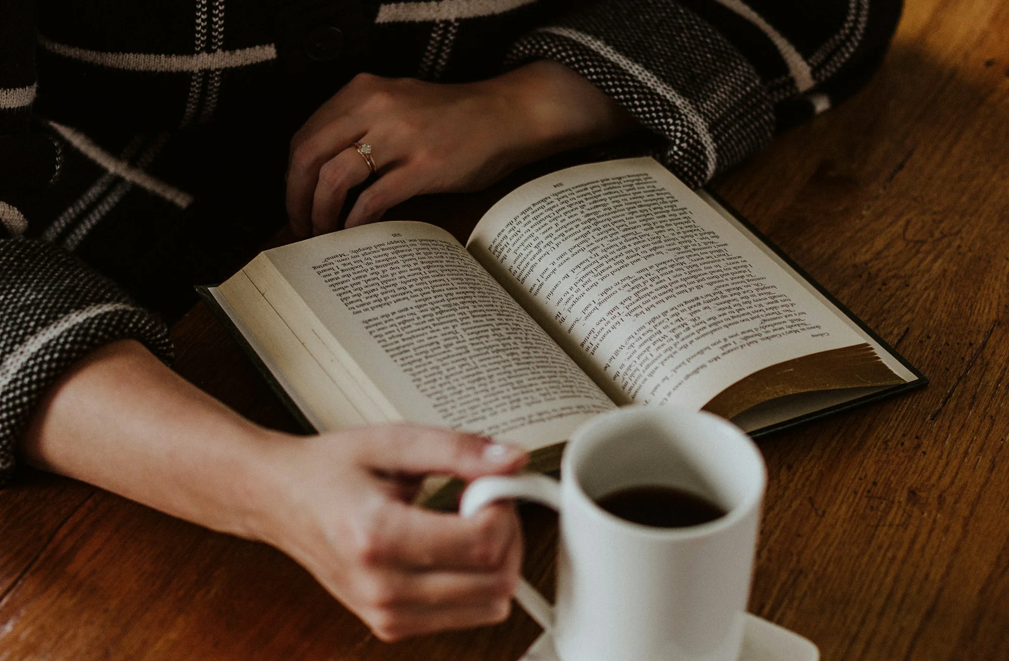 شخص يقرأ كتابًا مع كوب قهوة